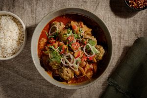 Lamb meatballs simmered in a rogan josh gravy, served topped with diced tomato, a spoonful of yoghurt, fresh coriander and sliced chilli, with steamed rice on the side